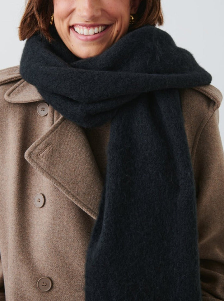 Person wearing a dark blue scarf and brown coat on a light background