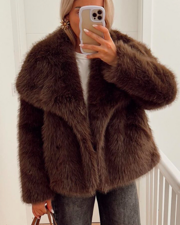Person wearing a brown fluffy jacket taking a mirror selfie.