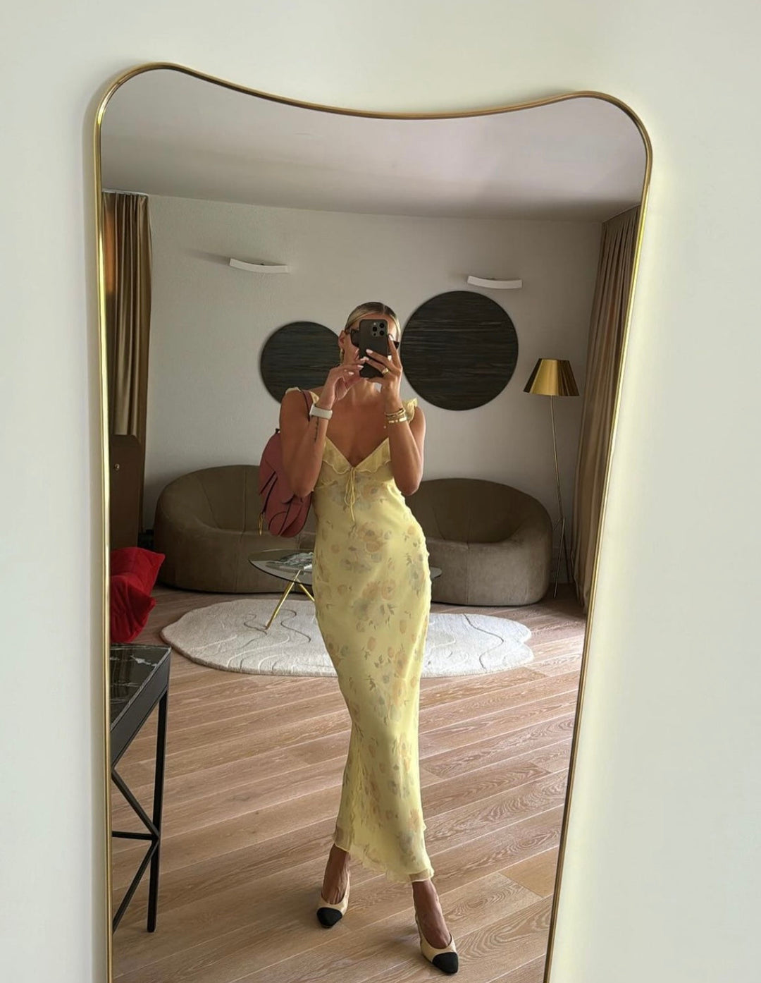 Person wearing a yellow dress taking a mirror selfie in an interior setting.
