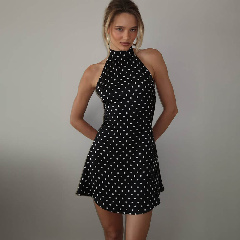 Woman wearing a black polka dot dress against a plain background