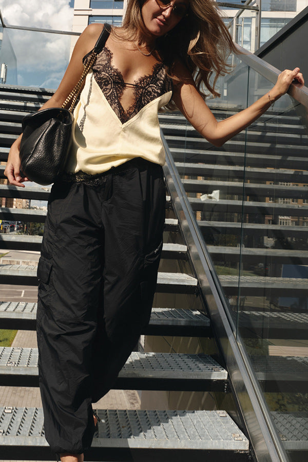 Woman in stylish outfit with black lace top and high-waisted black pants on outdoor steps.