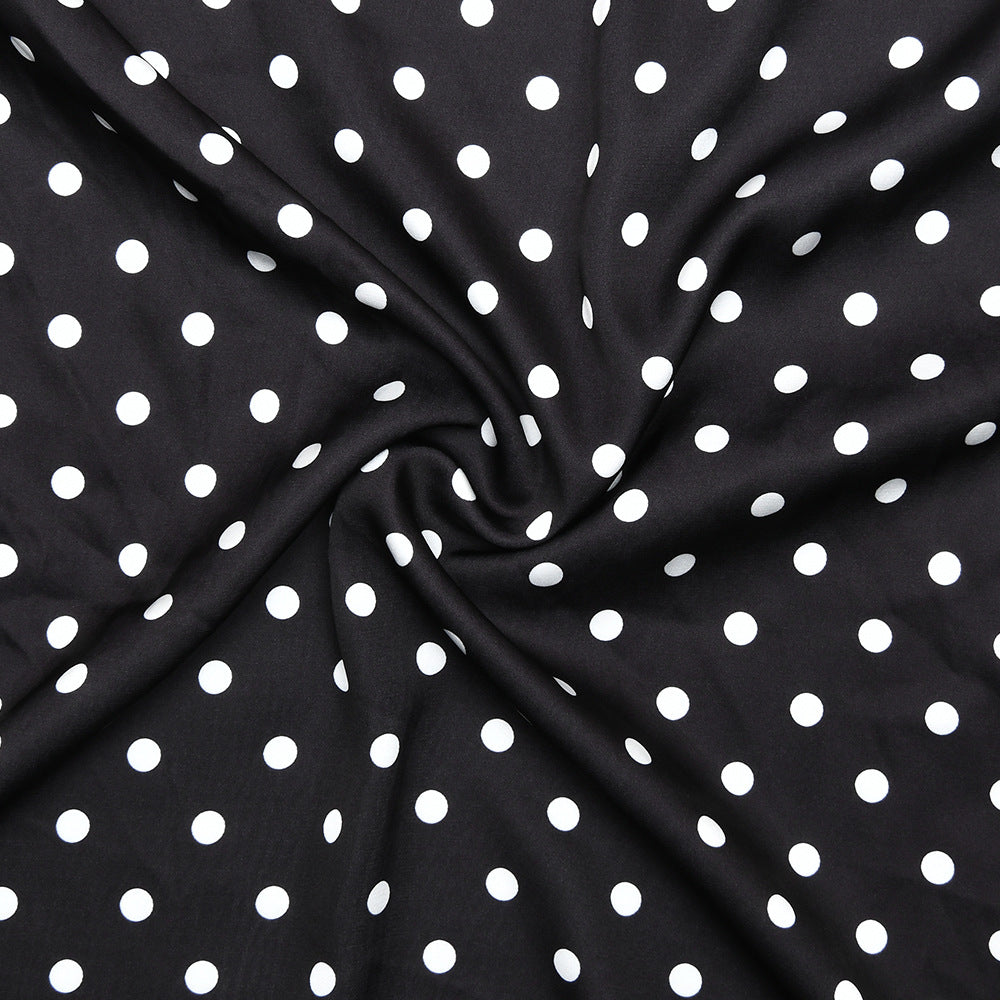 Black fabric with white polka dots, folded in a way that creates a circular pattern.