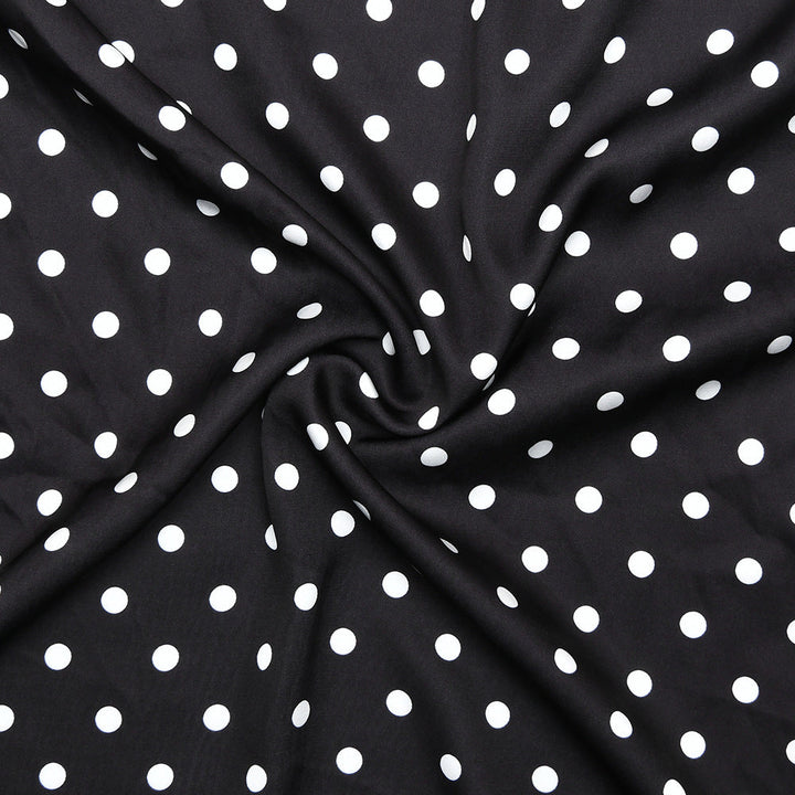 Black fabric with white polka dots, folded in a way that creates a circular pattern.