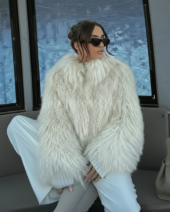 Person wearing a fluffy white jacket and sunglasses inside a vehicle.