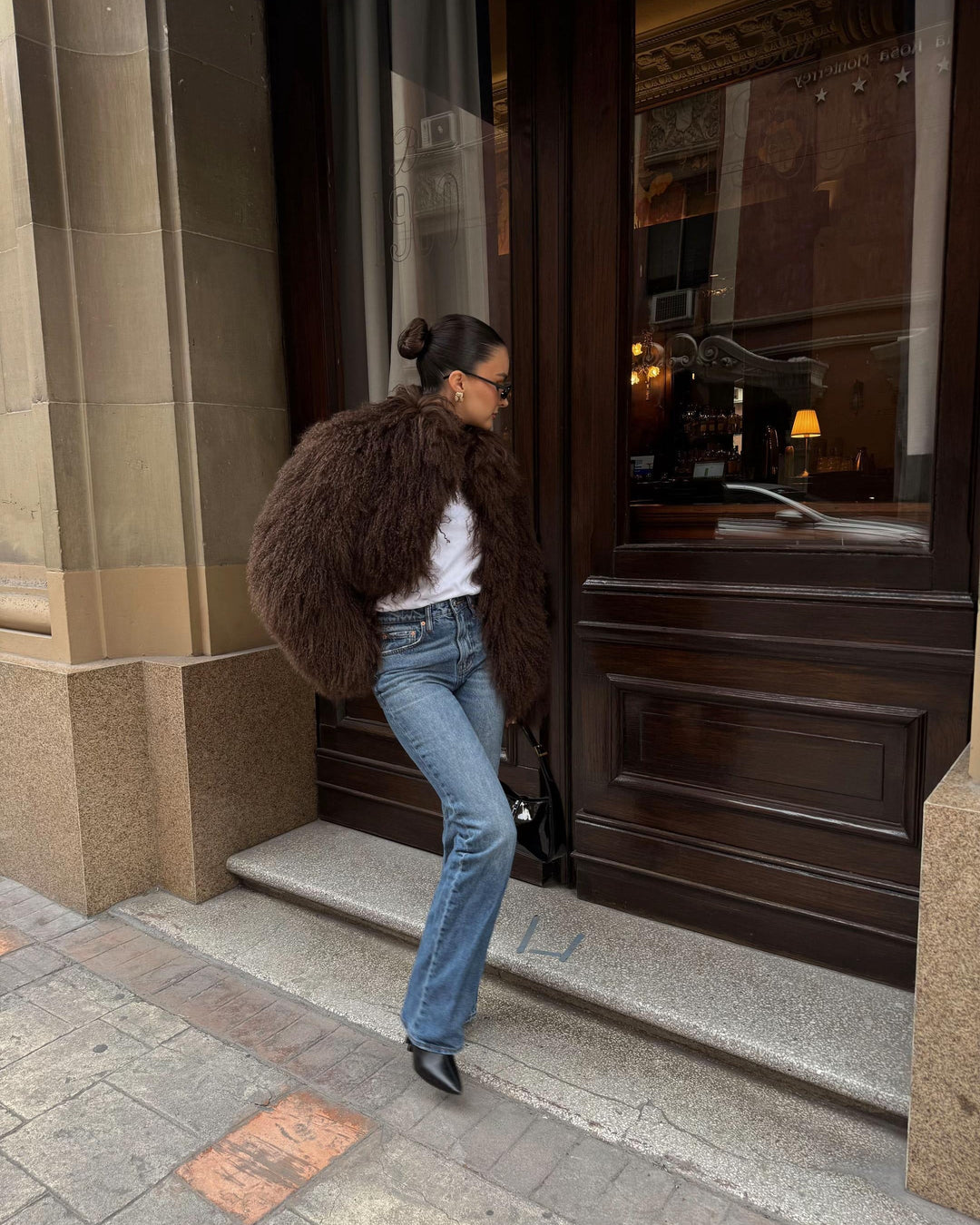 Person with a large brown fur coat entering a building