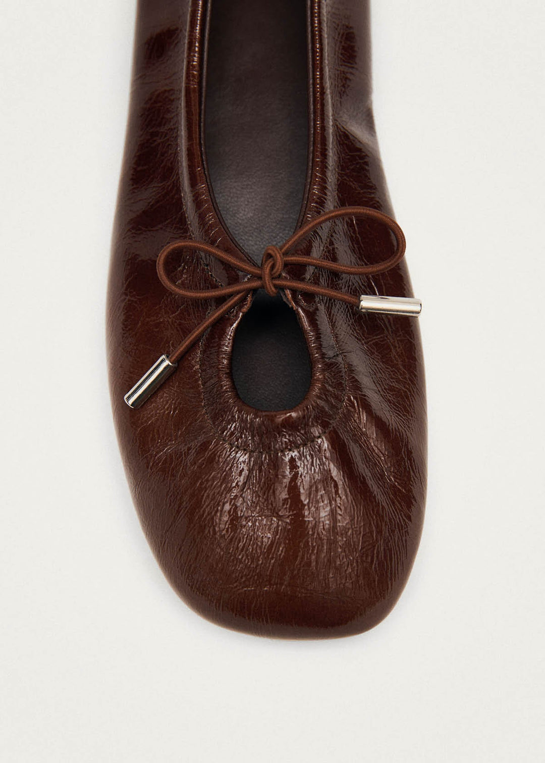 Brown leather ballet flat shoe with a bow on a white background